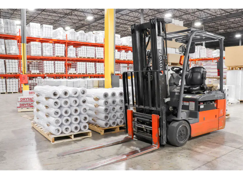 Rolls of Drytac media being moved in a warehouse using a forklift