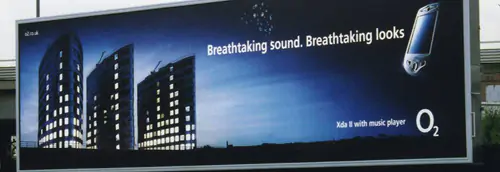 Advertisement for a music player. Three lighted buildings with backdrop of a night sky.