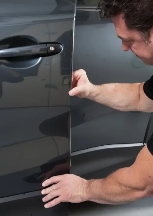 Man applying 849 Paint Protection Film to edge of grey car door.