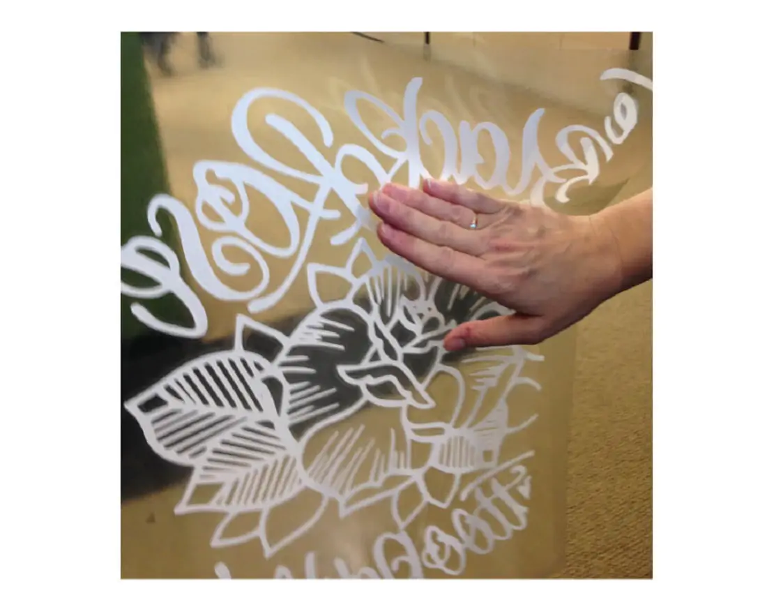 A white design and flower design of Sign-Ad Clear Removable, Clear Adhesive on a glass door 
