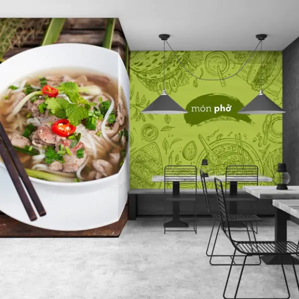 A restaurant with chairs and table, and a big green wall poster and a picture of pho